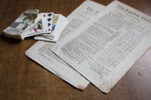 Under the Stamp Act of 1765, newspapers, playing cards, and other paper products were required to have an official stamp on them. Red tax stamps are visible on the bottom of these original newspapers on display at Michilimackinac. 