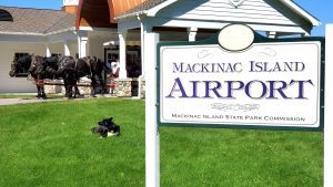 A picture of the Mackinac Island Airport sign with horses in the background.