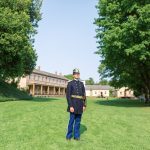 A soldier in dress uniform standing on the parade ground at Fort Mackinac.