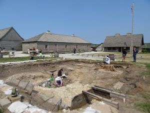 The archaeology dig site at Colonial Michilimackinac, with people in white shirts in the dig site. 