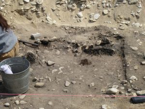 The archaeological dig at Colonial Michilimackinac with dirt, rocks, a large hole, and ropes. 
