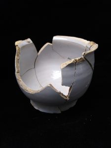 Fragments of a white ceramic bowl put back together. 