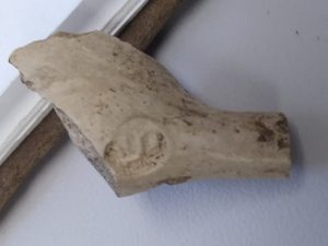 A fragment of a white pipe made of clay. 