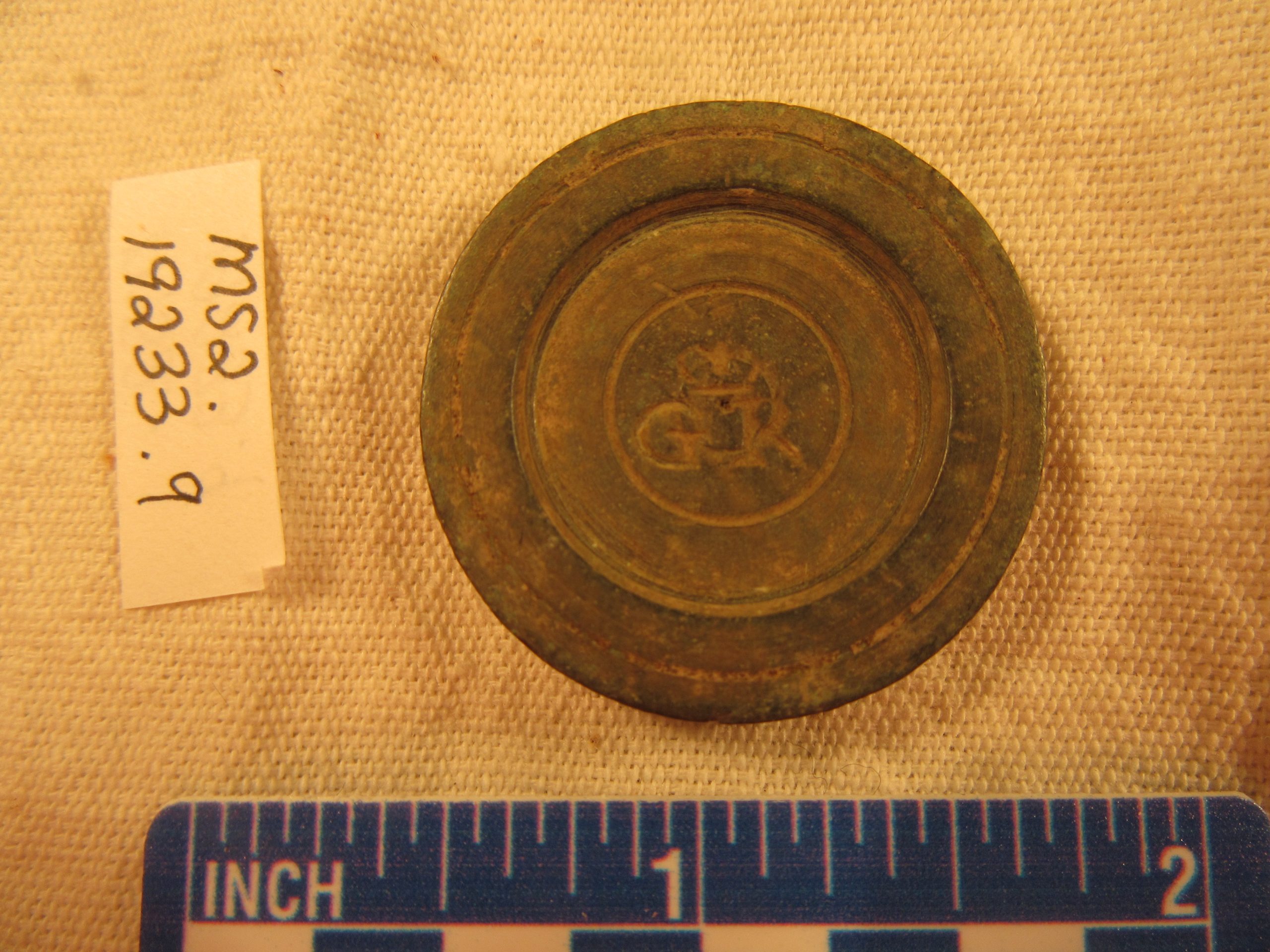 A brass weight with a ruler and collections number
