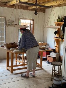 A person wearing historic clothing standing at a wooden table